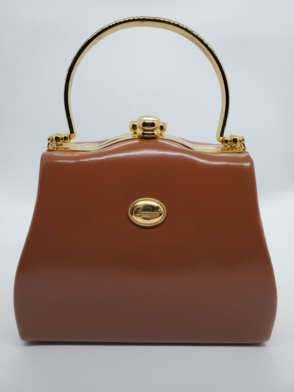 front view of tan and gold hard shell retro handbag