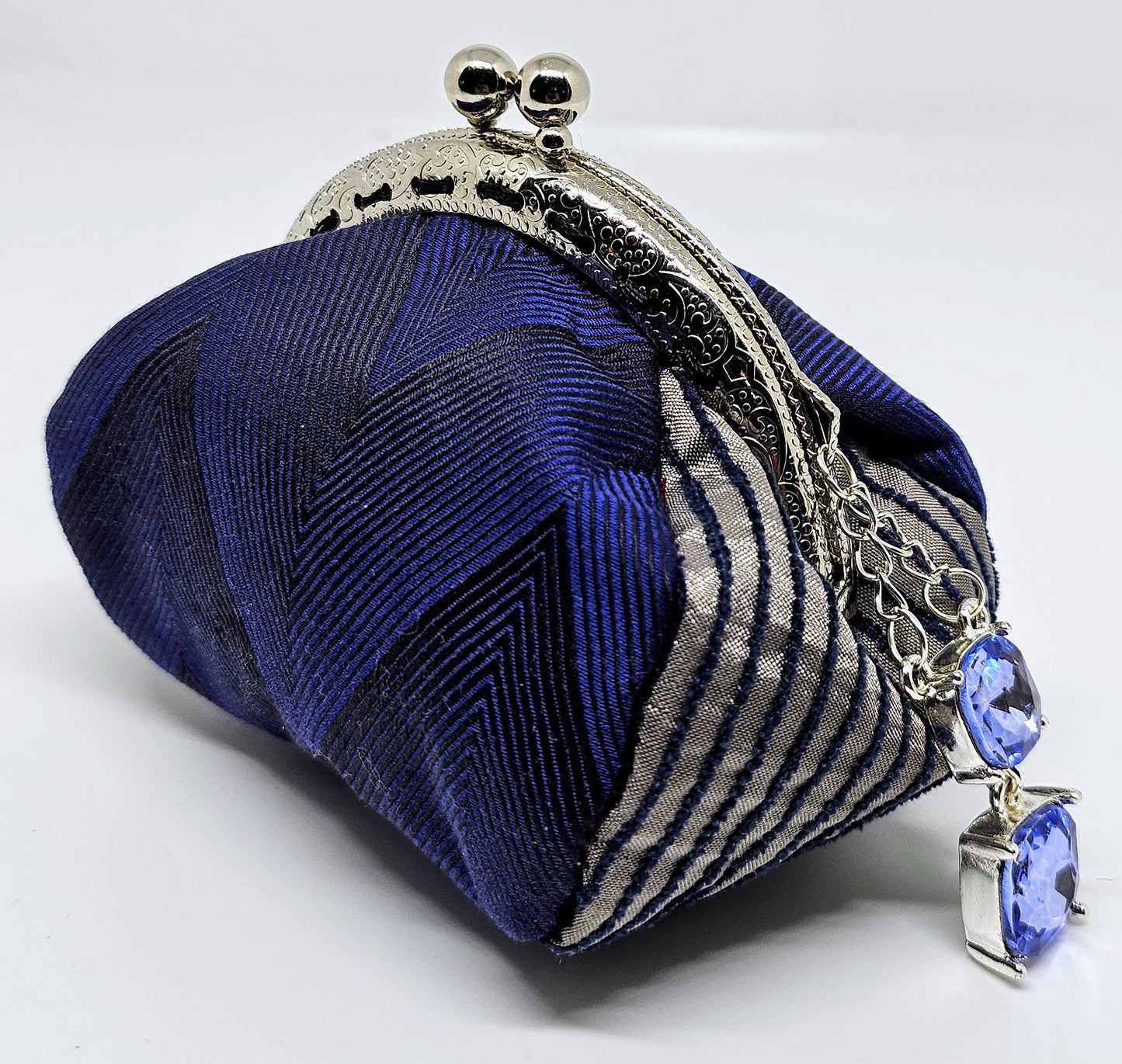 Side view of Navy chevron print kiss clasp coin purse with silvery blue jewel charm