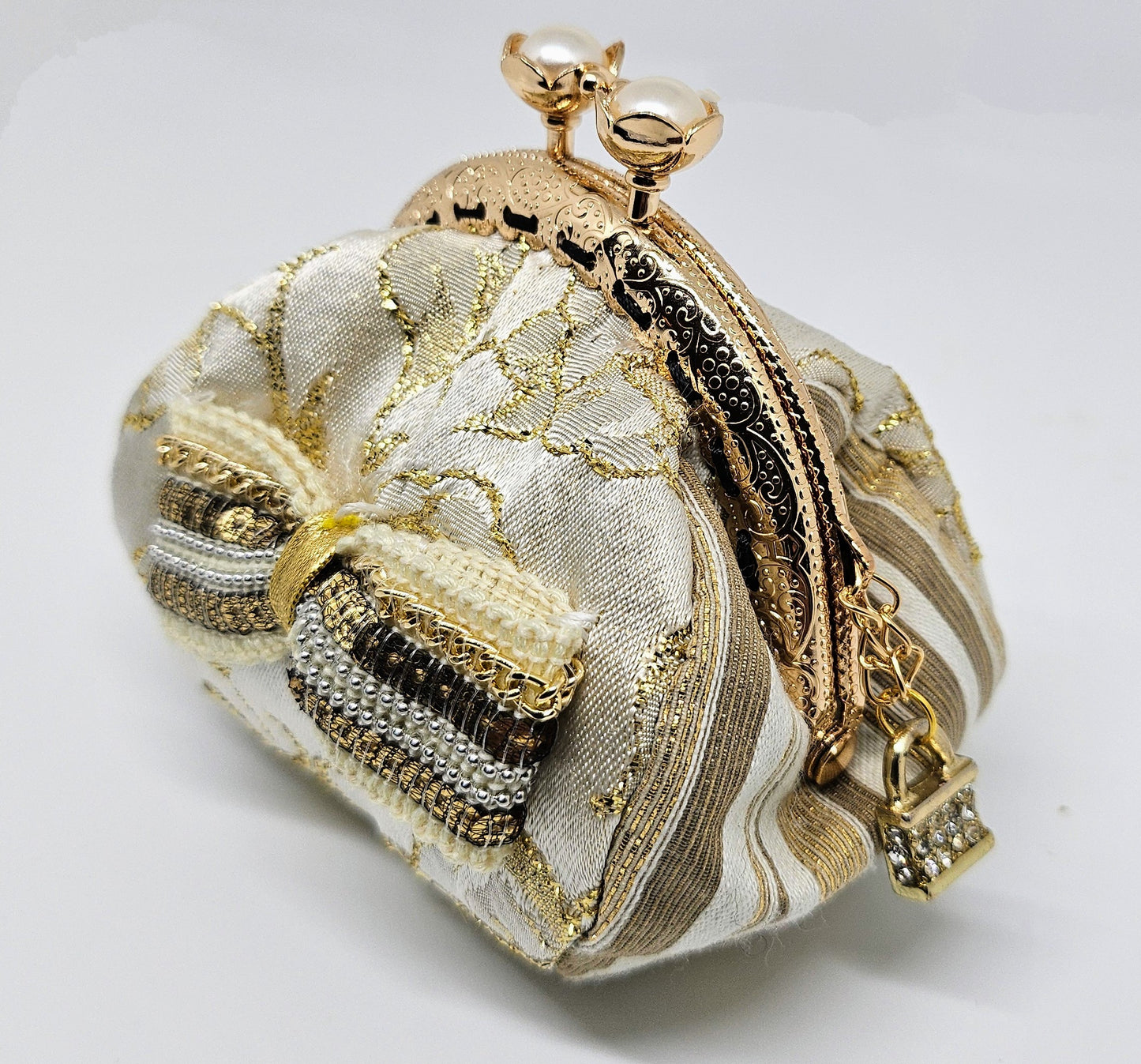 Side view of Ivory and gold floral brocade kiss clasp coin purse with sequin and chain bow and ornate jeweled padlock charm