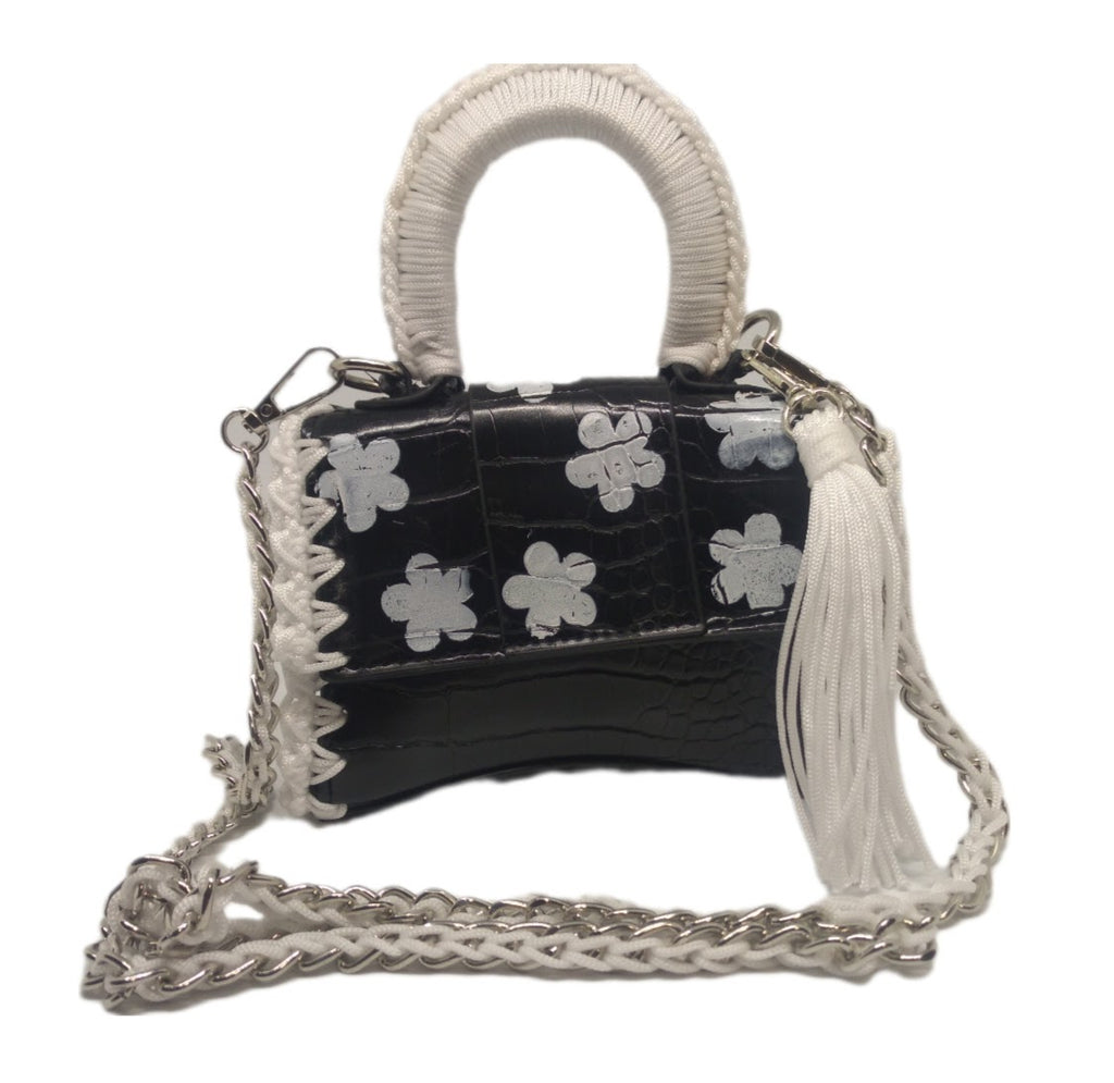 Front view of Black and white vegan leather handbag with crochet and distressed flower details