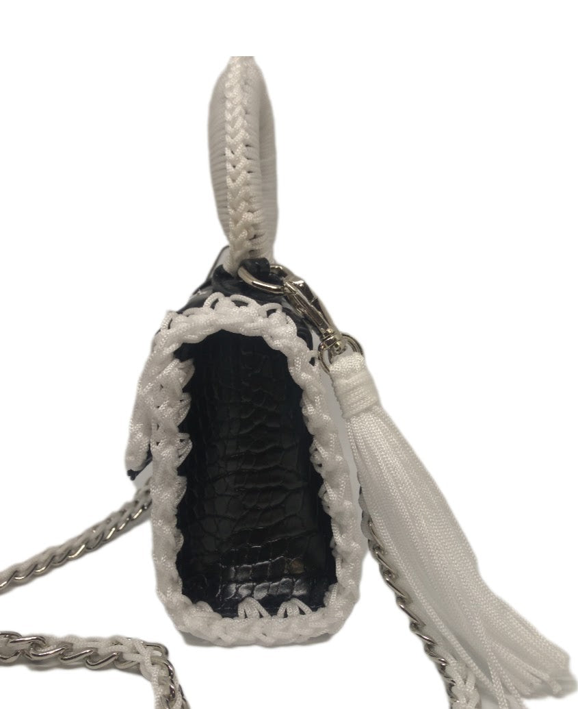 Side View of Black and white vegan leather handbag with crochet and distressed flower details