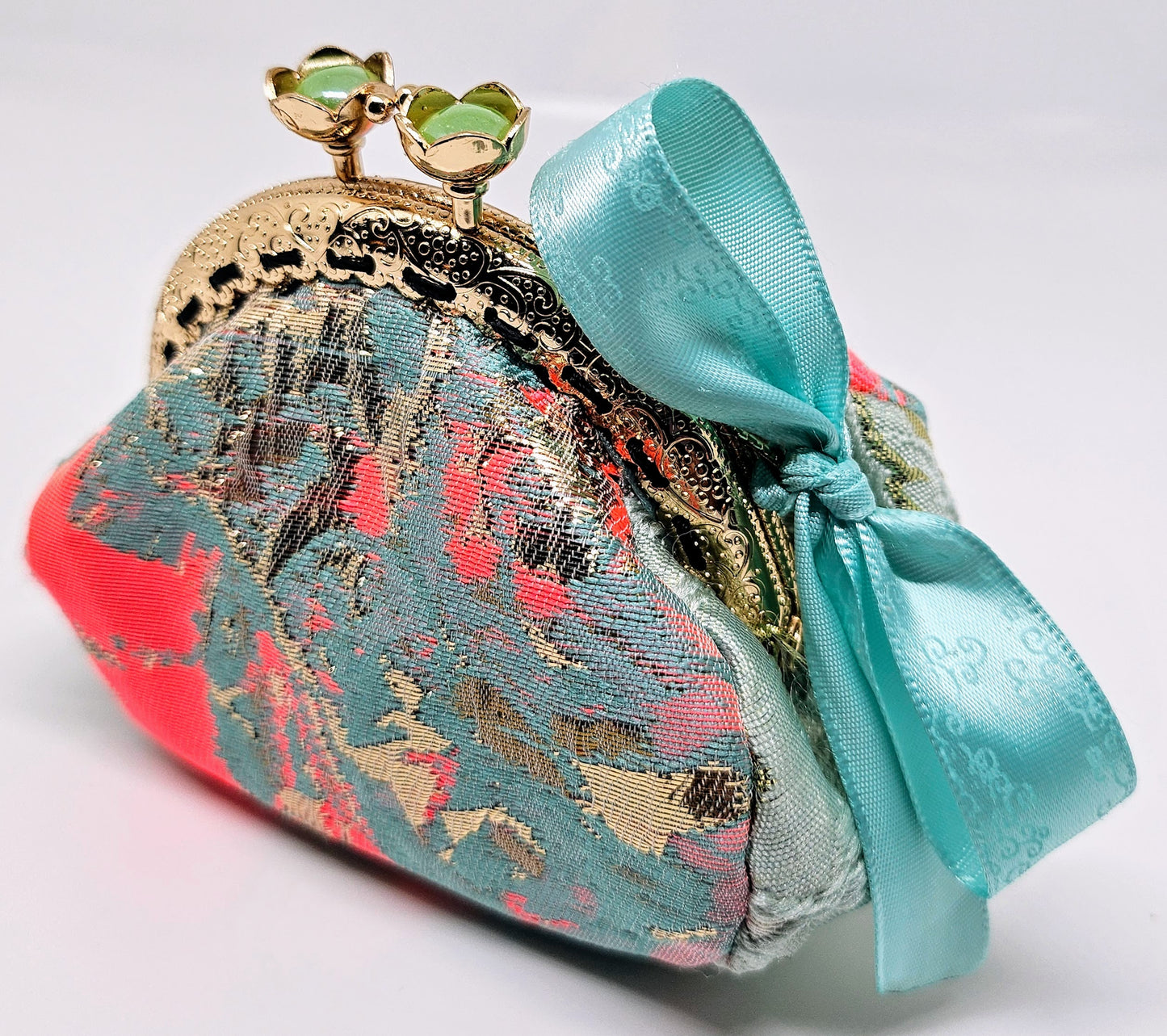 Side view of Mint and coral kiss clasp coin purse with laser etched ribbon bow