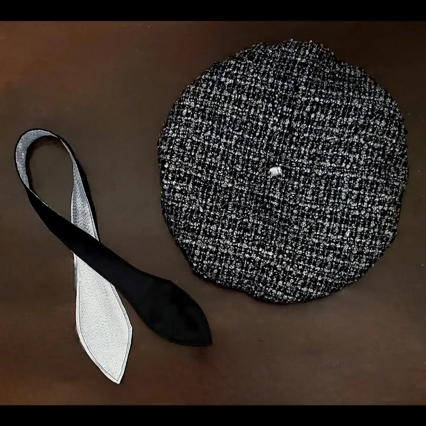 Black and silver tweed beret and matching scarf on brown background