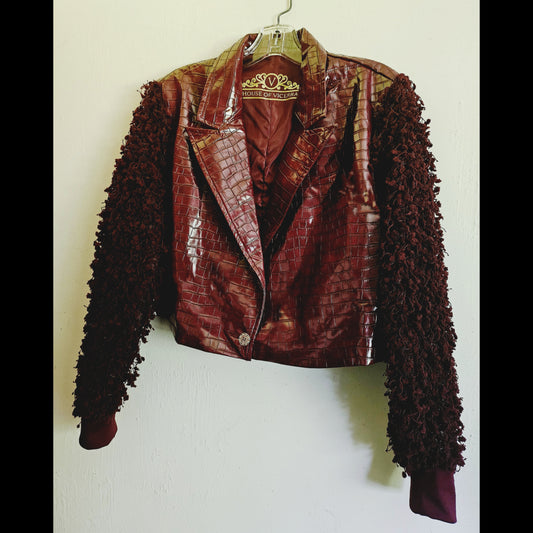 Side front view of burgundy croc embossed cropped jacket with fringe knit sleeves