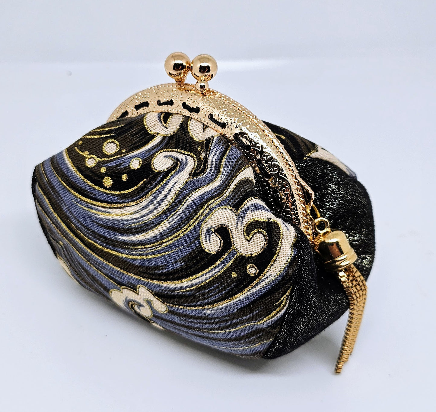Side view of Wave print kiss clasp coin purse with gold tassel