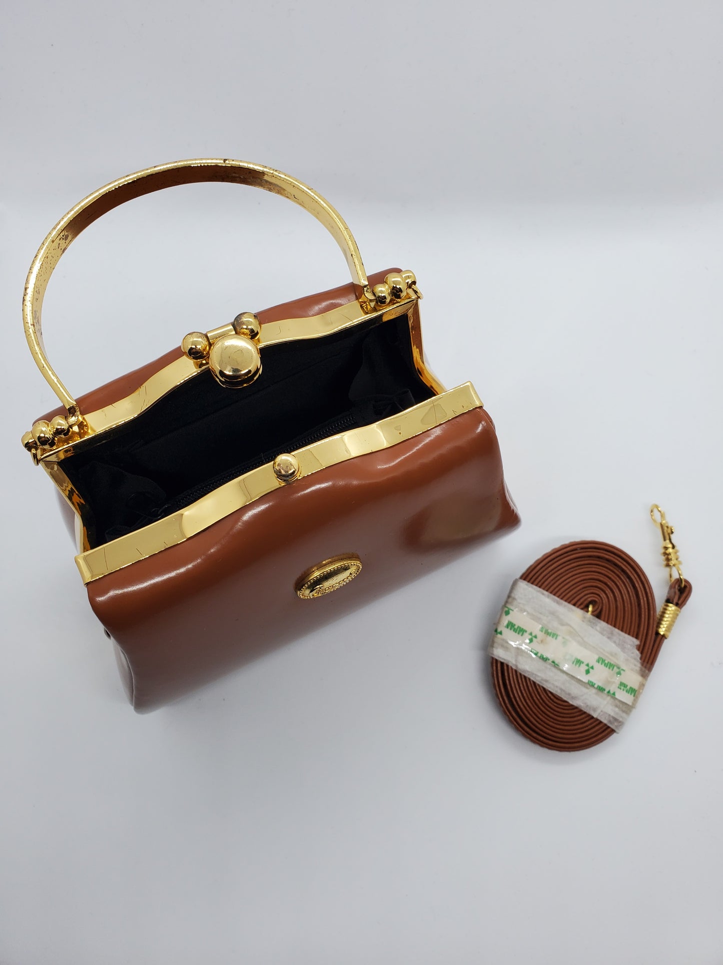 top view of tan and gold hard shell retro handbag with strap