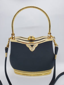 Close up front view of Smooth black handbag with ornate gold frame and handle with rhinestone accents and crossbody strap