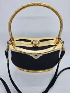 Top view of Smooth black handbag with ornate gold frame and handle with rhinestone accents and crossbody strap