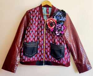 Front view of striped print bomber jacket with crocodile print embossed sleeves, upcycled denim pockets and handmade flower details