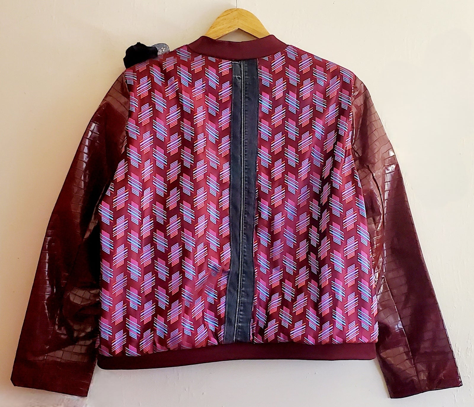 Back view of striped print bomber jacket with crocodile print embossed sleeves and denim strip at center back