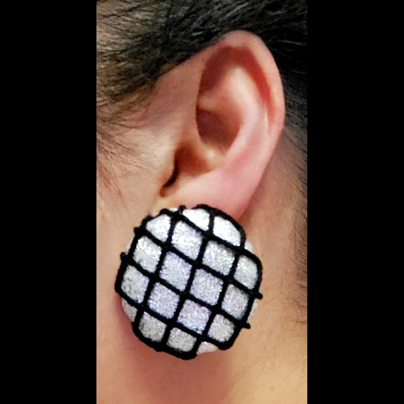 Silver and fishnet button earring worn on ear