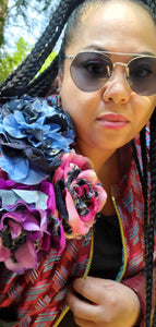 Model with braids and sunglasses showing handmade flower detail on striped bomber jacket.