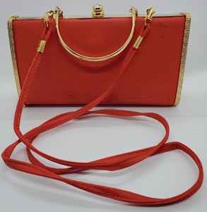 front view of Red and gold vintage hard shell bag with matching strap
