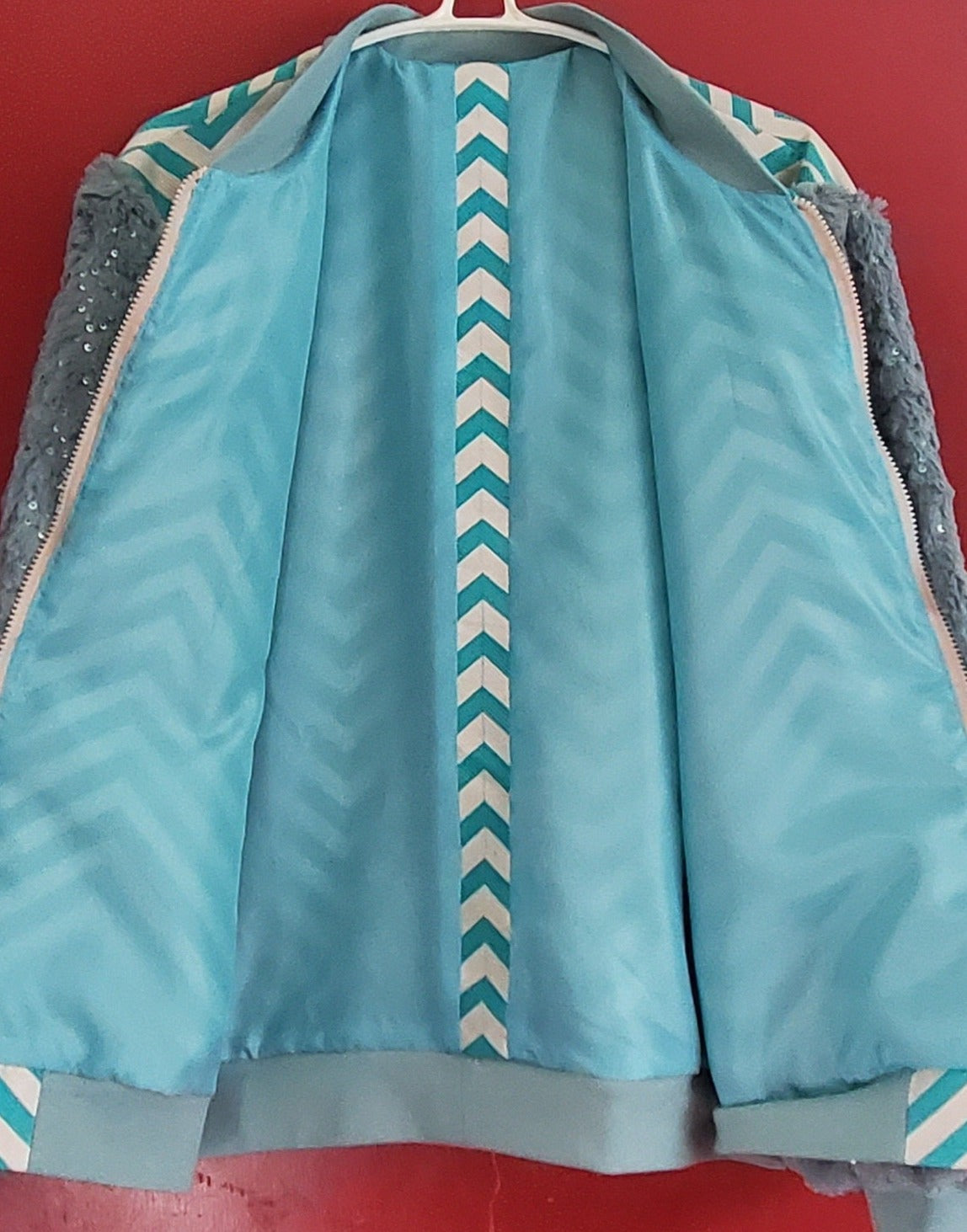 Lining view of Turquoise chevron print bomber jacket with sequined fur sleeves