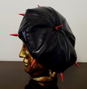 back view of gold buddha head wearing a beret with spikes and a tie dye top