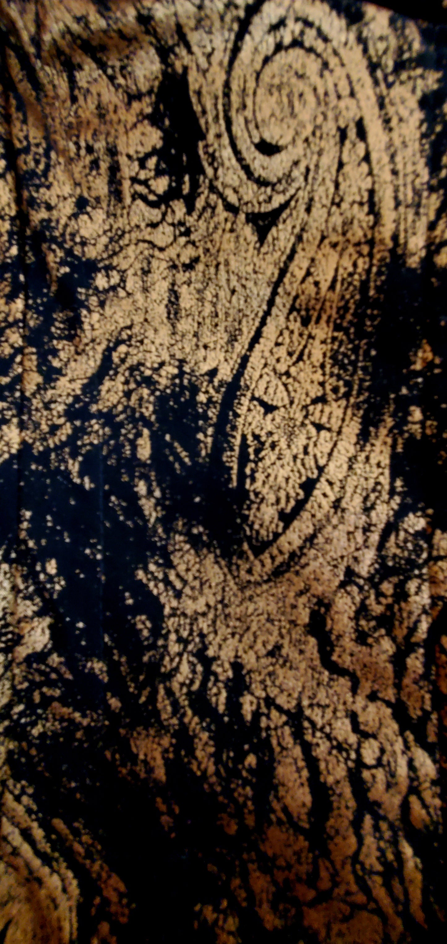 Close up of paisley fabric of 2 piece black and gold paisley suit with lace wing epaulettes