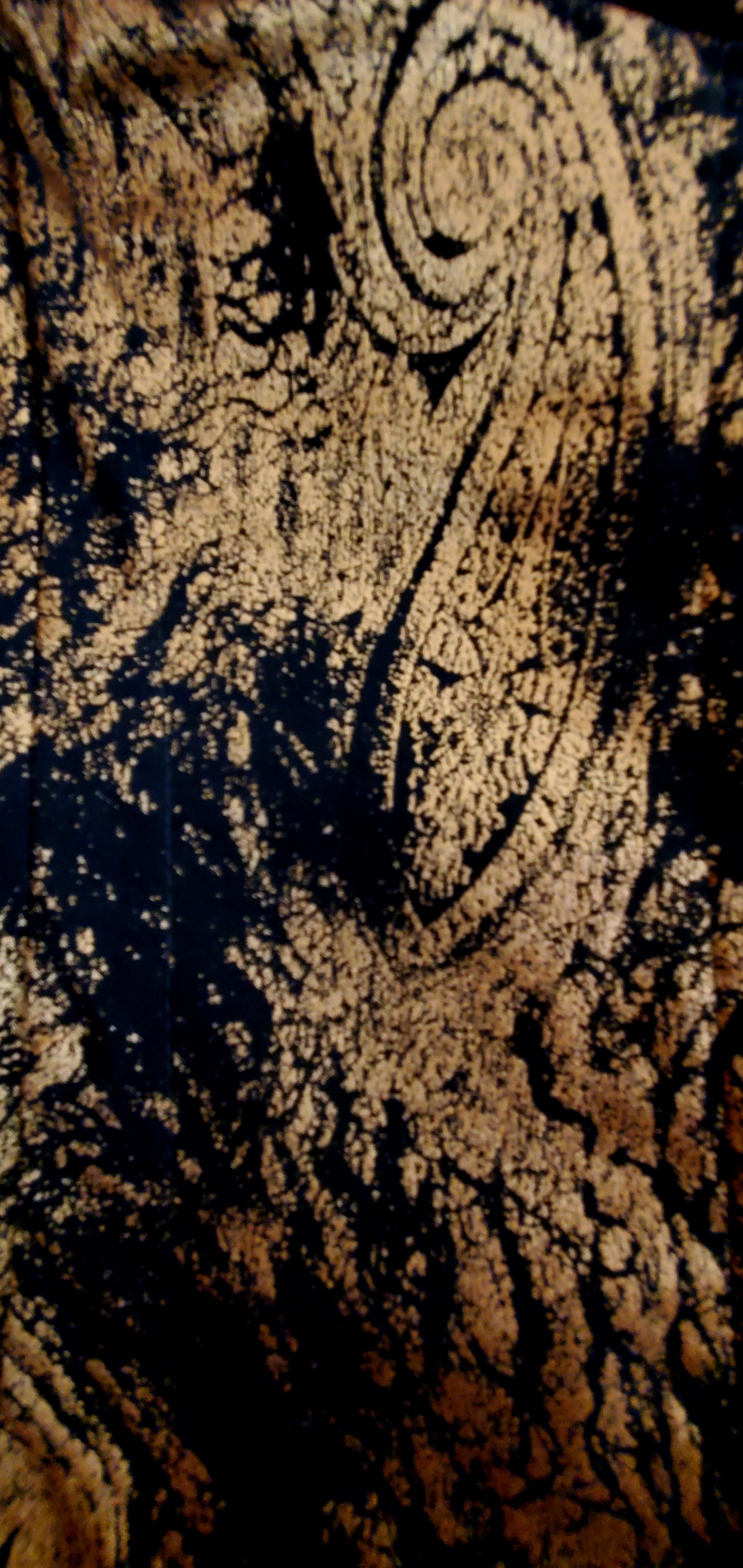 Close up of paisley fabric of 2 piece black and gold paisley suit with lace wing epaulettes