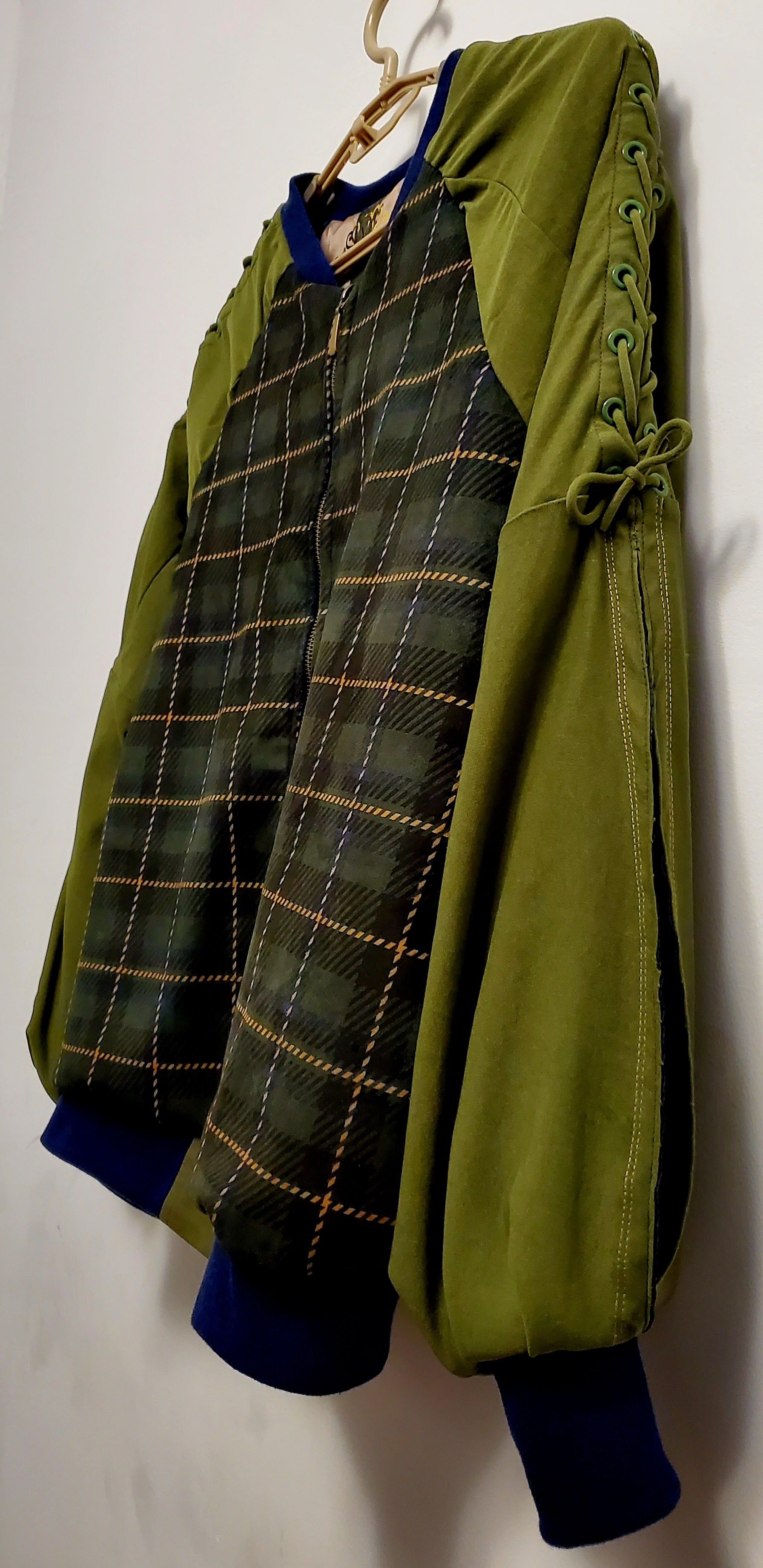 side view of Forest green plaid bomber jacket with split sleeves and laced shoulder details.