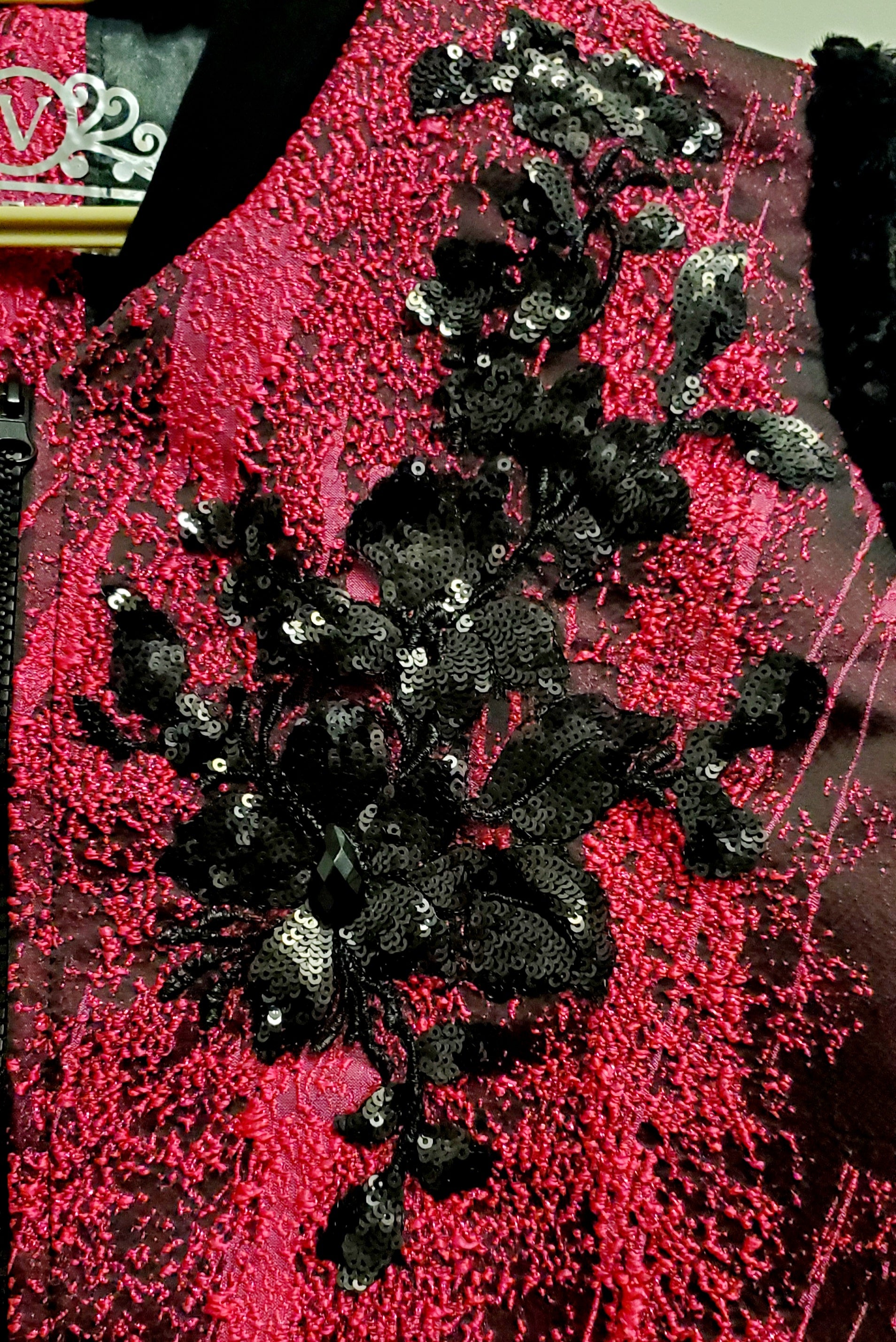 close up view of black sequin applique of Fuchsia and black bomber jacket with faux fur sleeves and sequin applique details