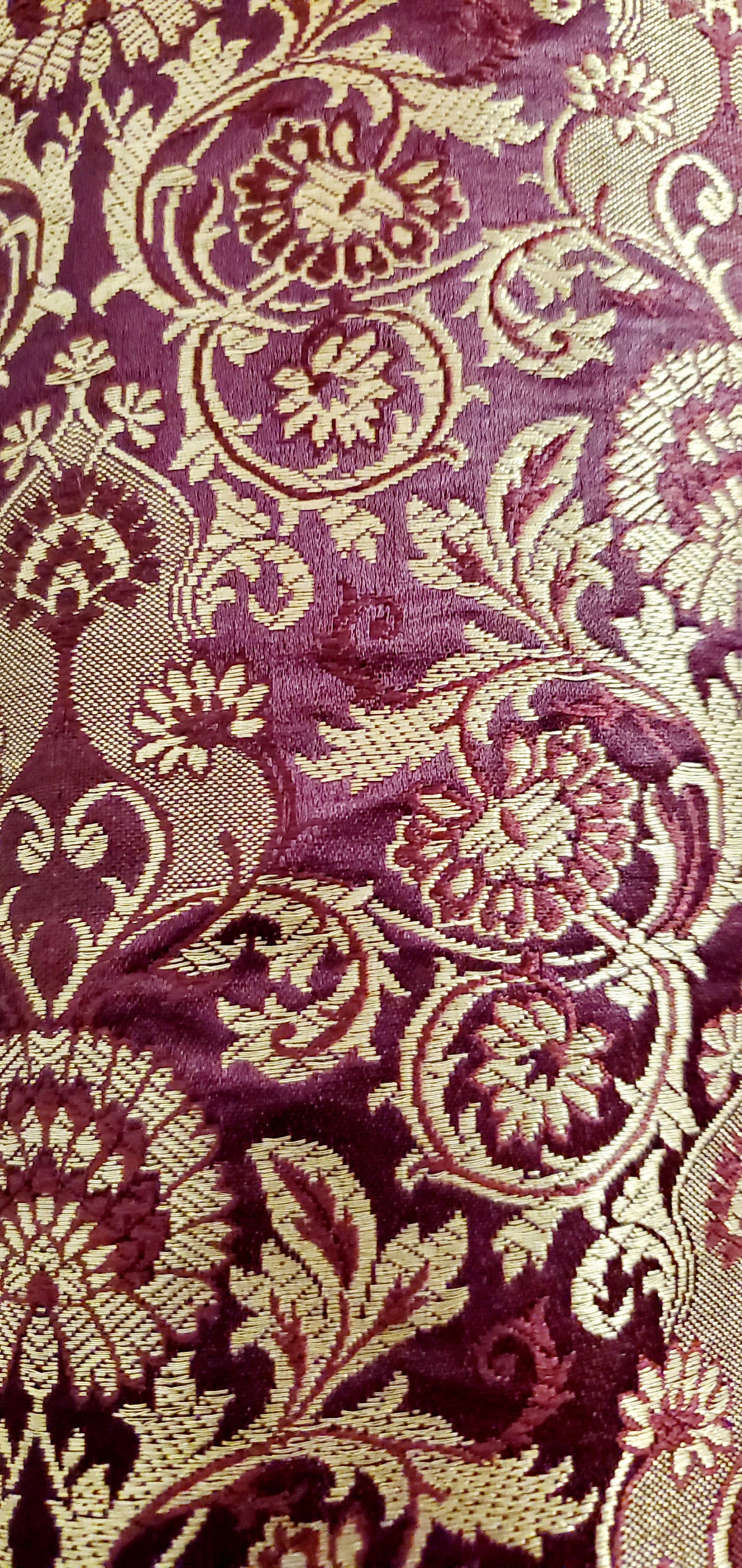 close up fabric view of Burgundy corduroy bomber jacket with metallic gold sleeve and knot closures