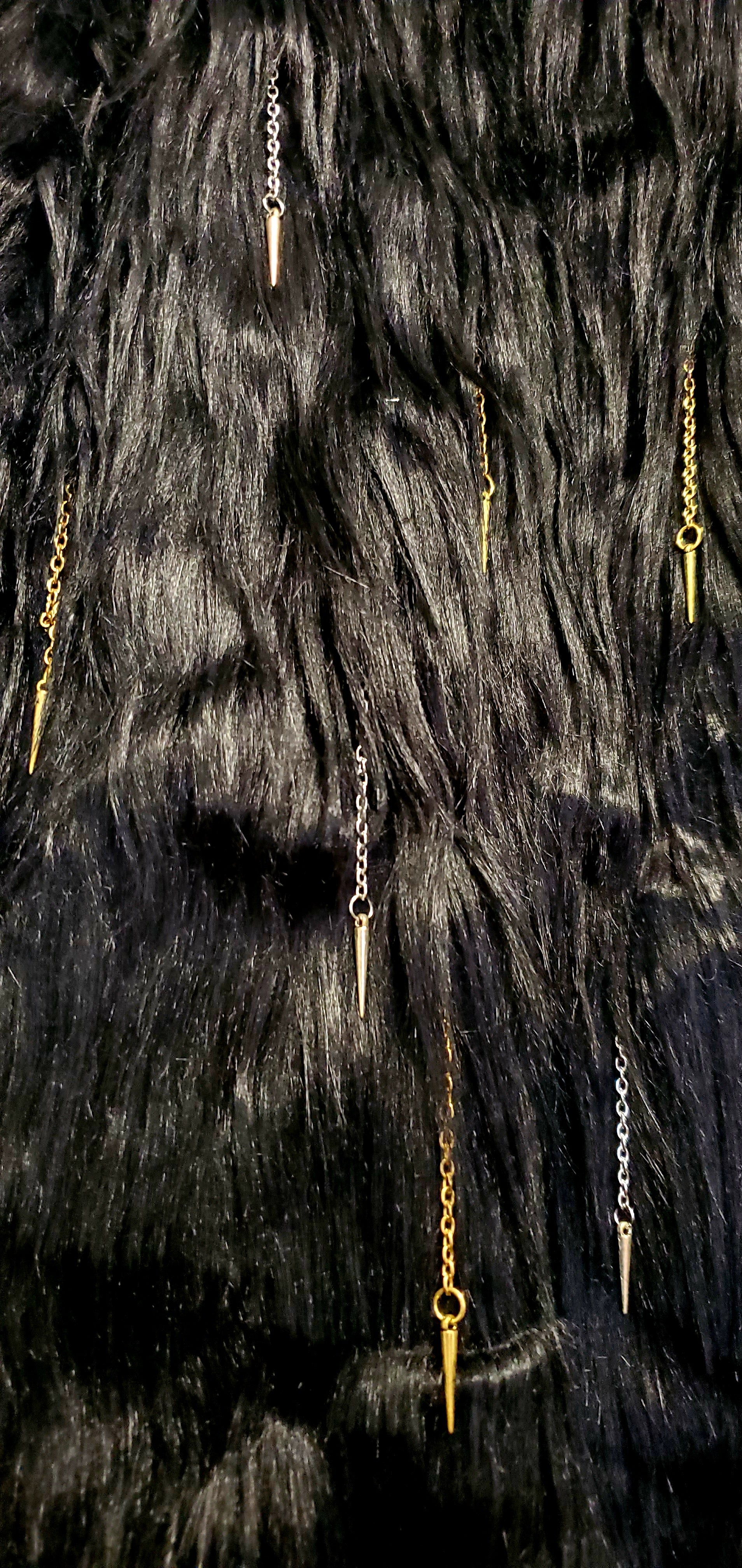 close up view of faux fur of black coat with chain and spike details 