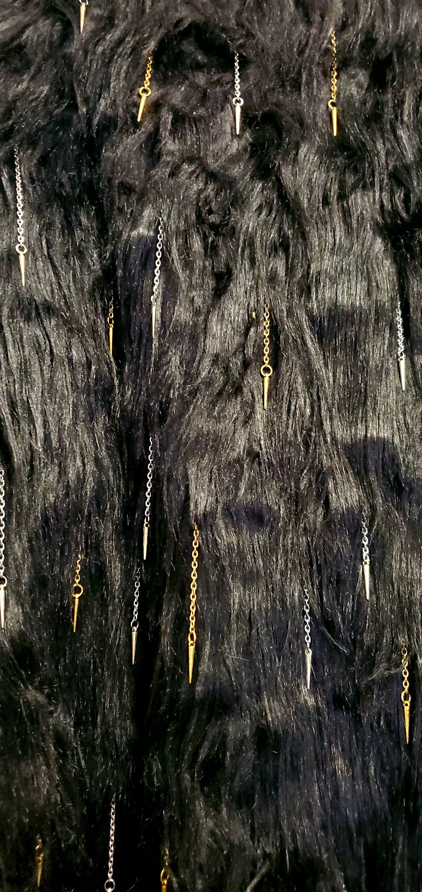 close up view of faux fur of black coat with chain and spike details 