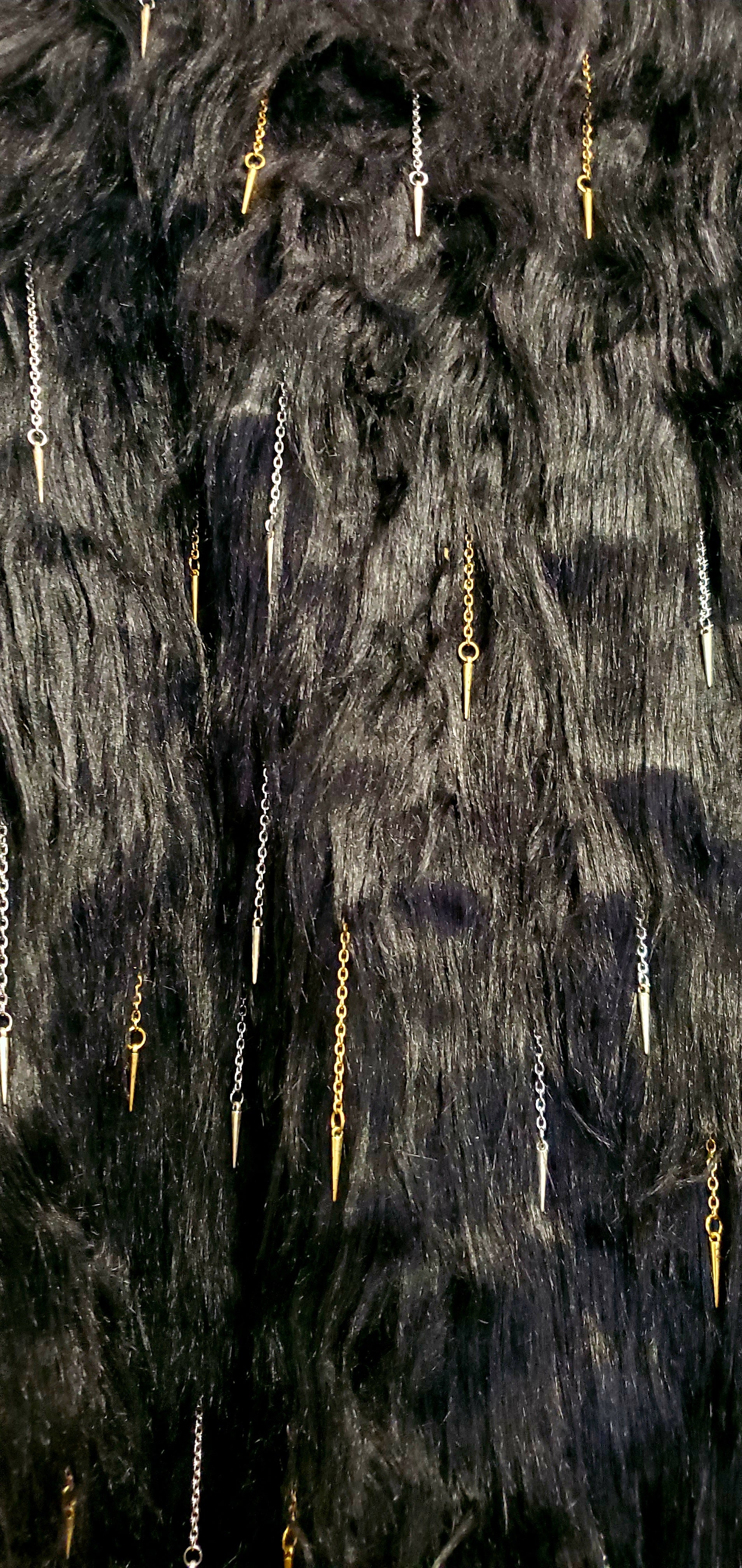close up view of faux fur of black coat with chain and spike details 
