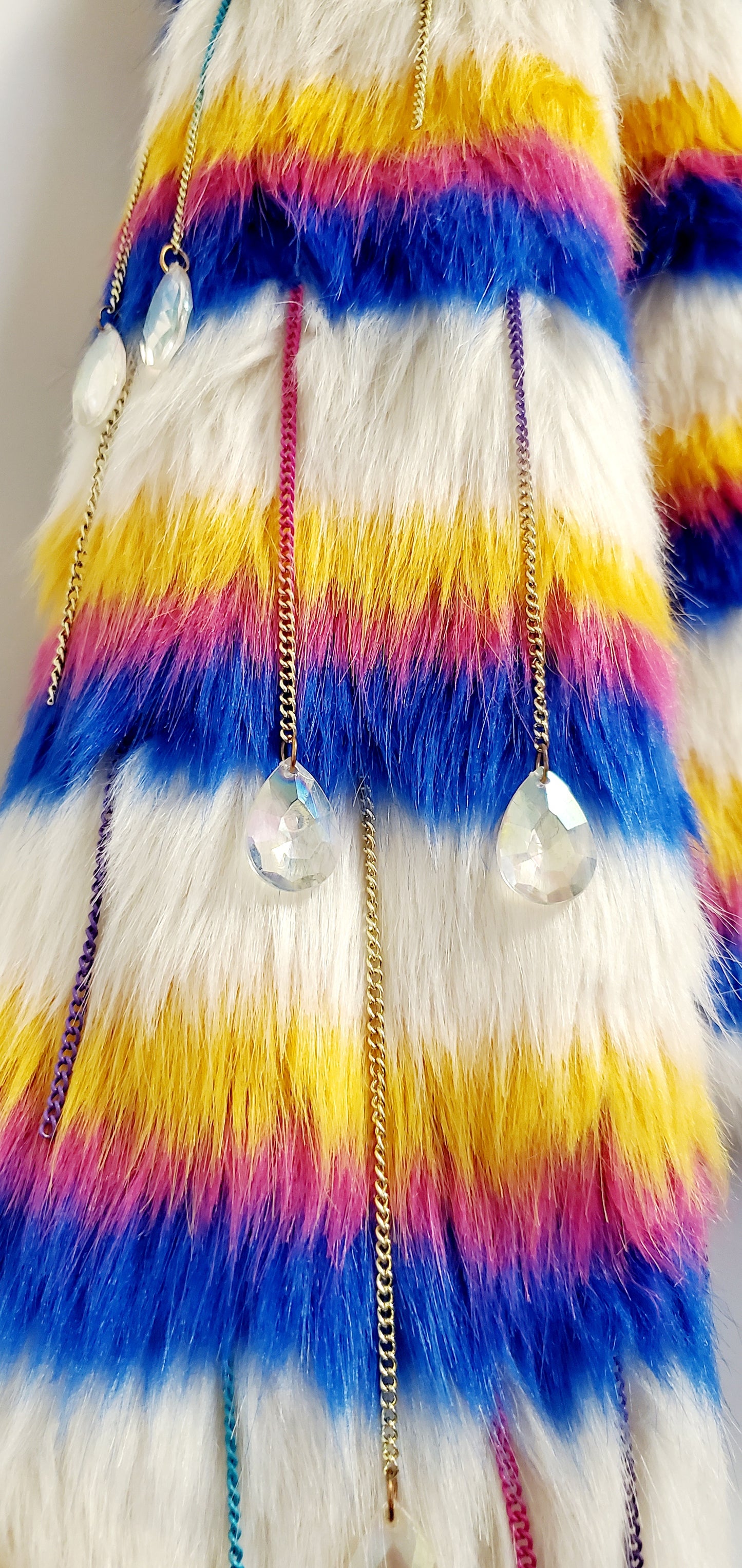 close up view of faux fur of white rainbow striped faux fur coat with chain details