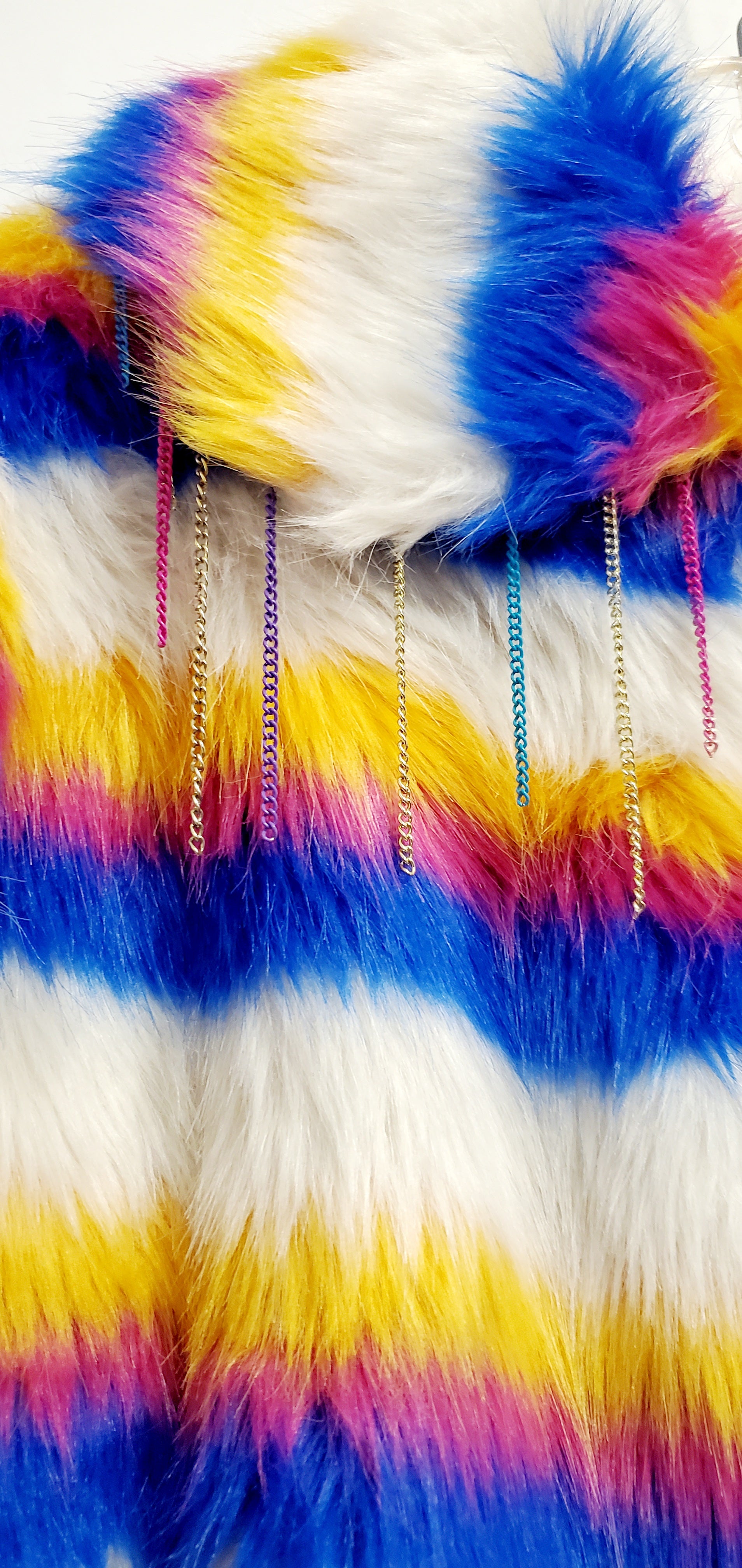 close up view of faux fur of white rainbow striped faux fur coat with chain details