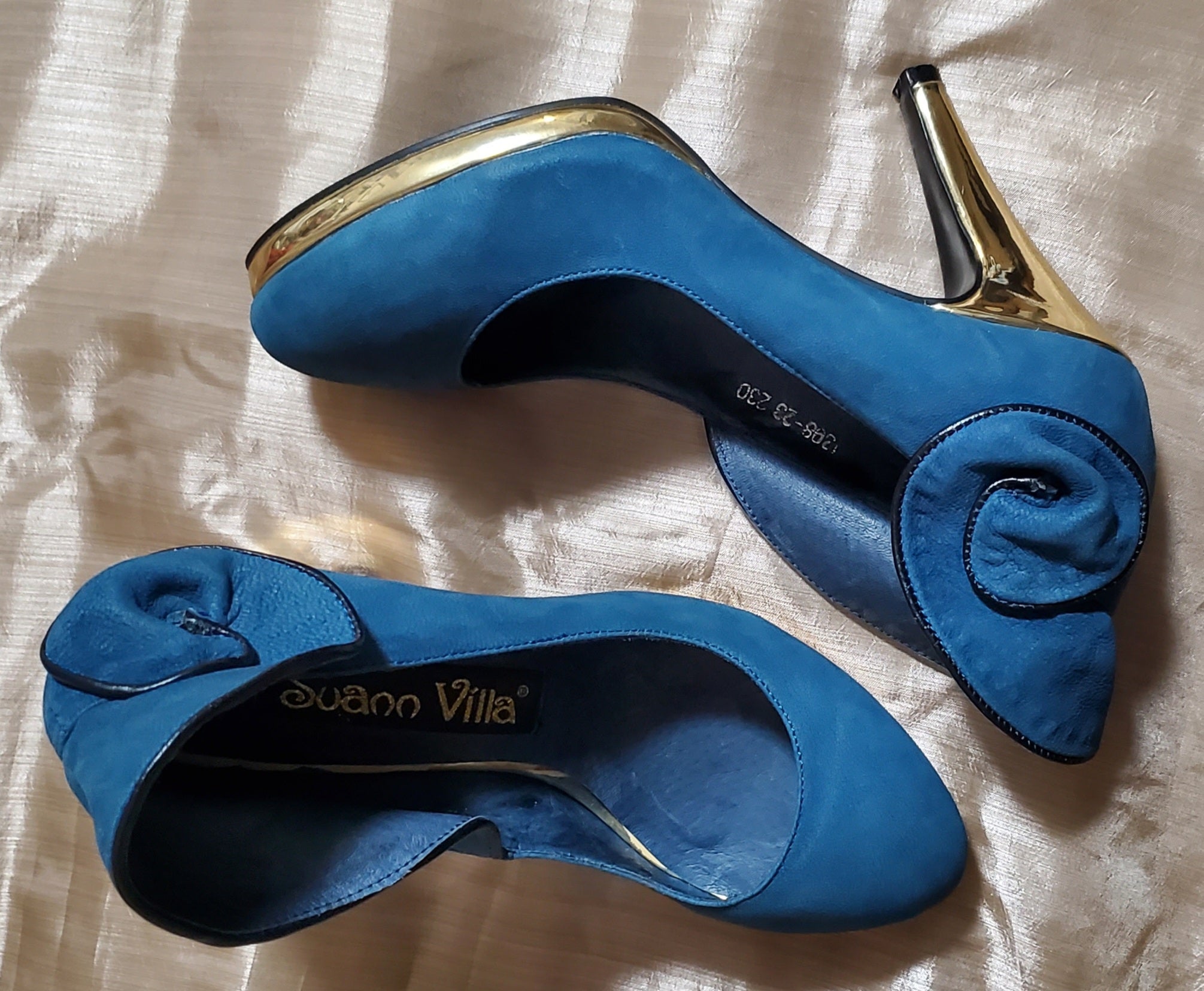 Top view of Suann Villa blue and gold leather pumps with ruffle details