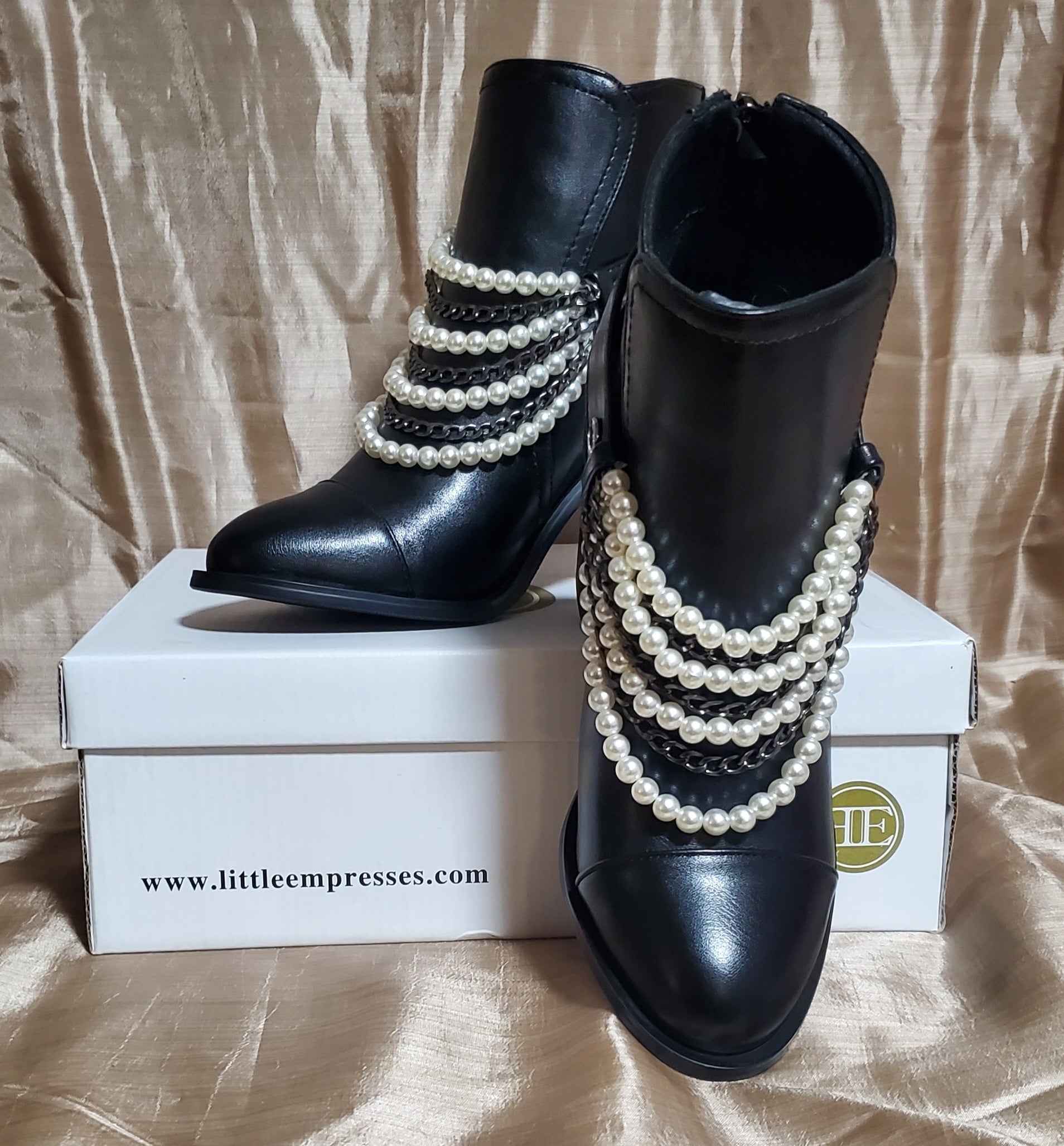 Styled photo of Black booties with pearl and chain details