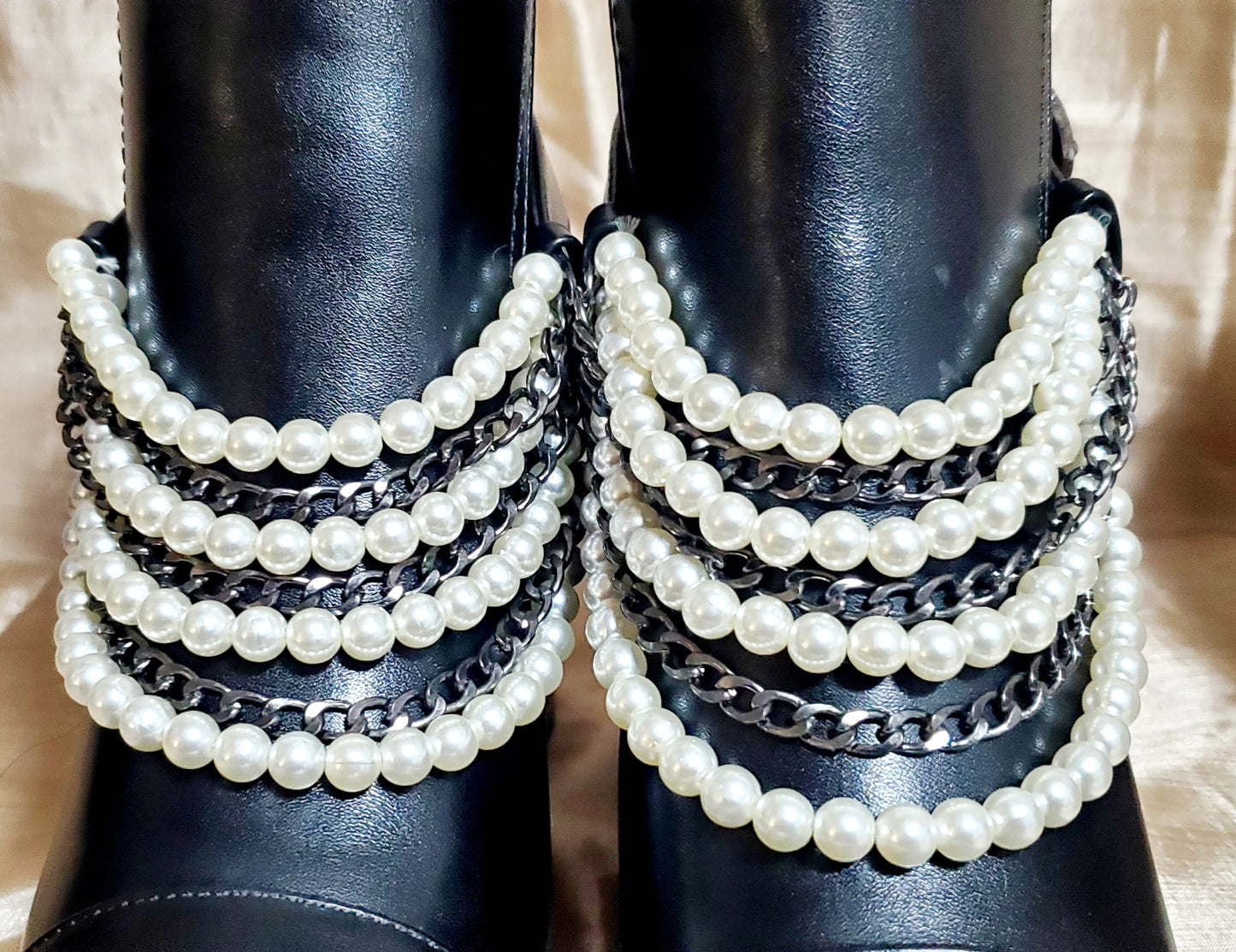 Close up view of Black booties with pearl and chain details