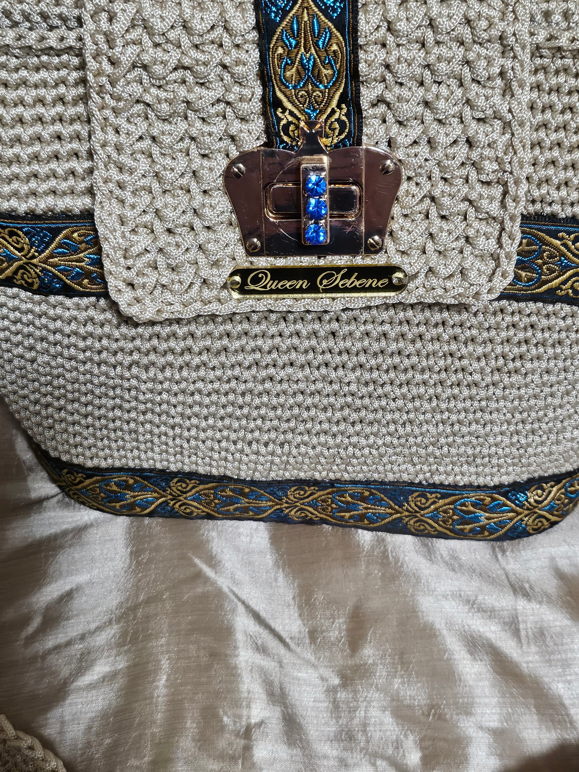 Close up Front view of Cream coloured crochet handbag with Teal and Gold paisley trim