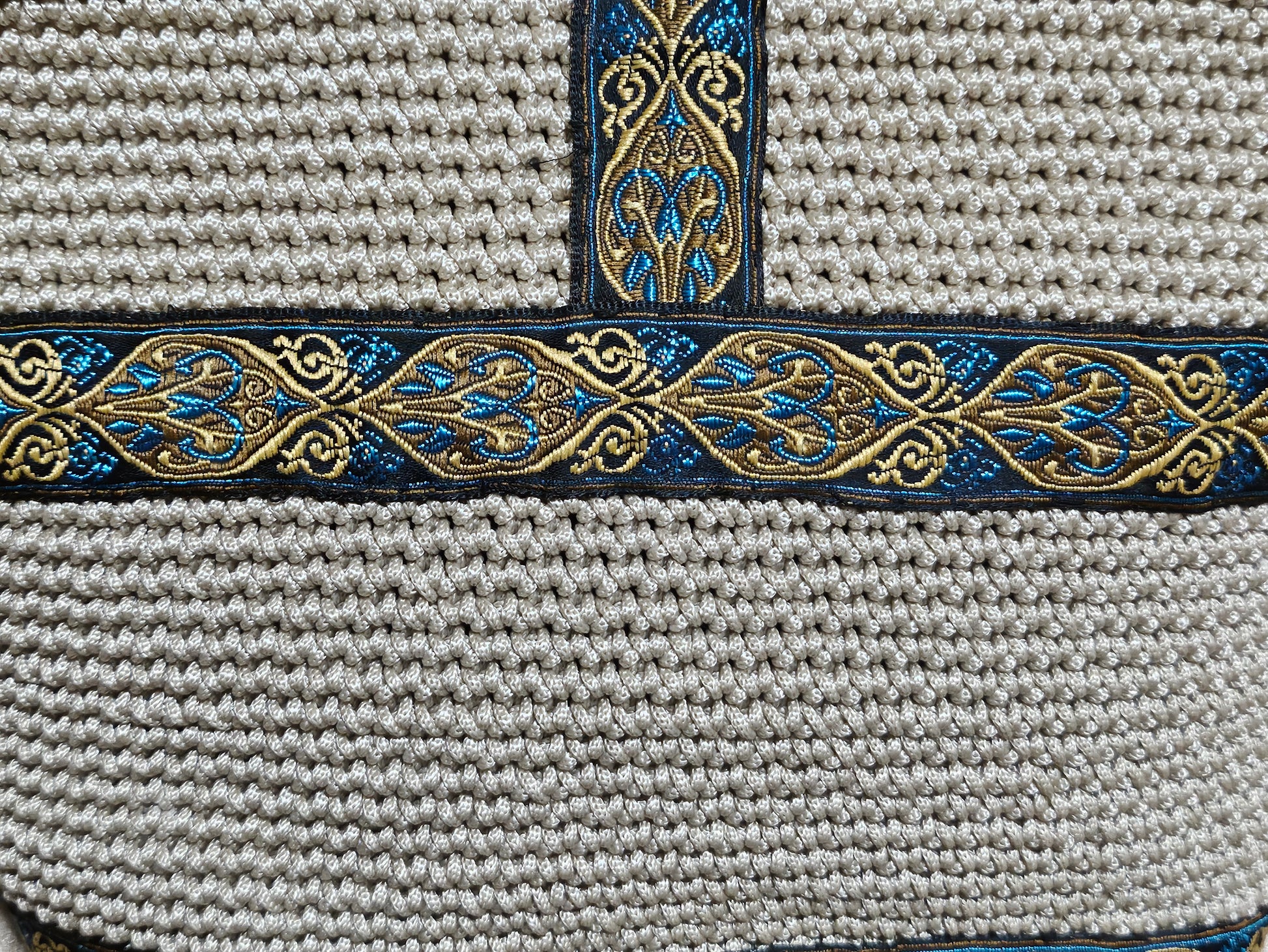 Close up back view of Cream coloured crochet handbag with Teal and Gold paisley trim