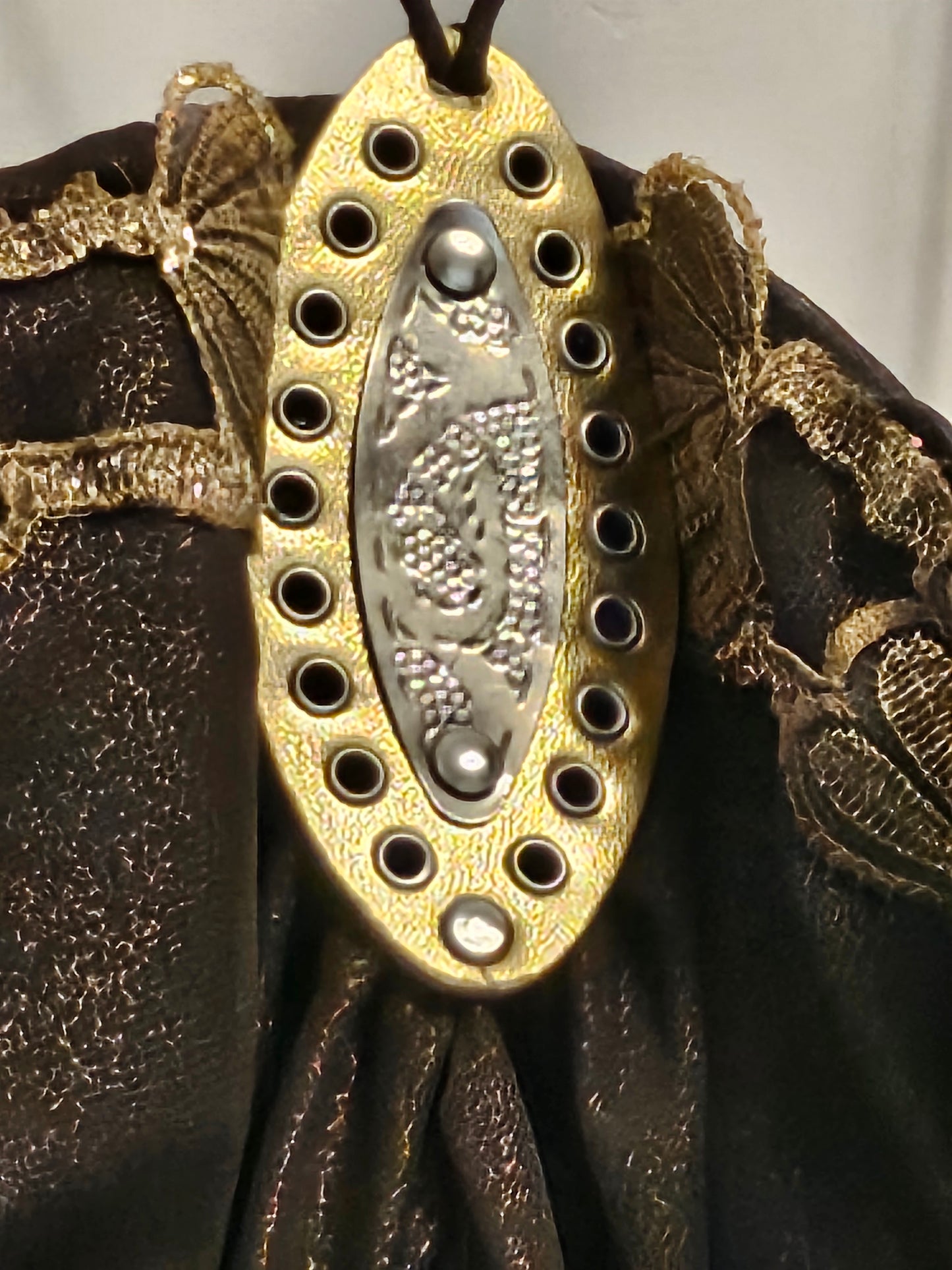 close up view of medallion detail on  Upcycled ruched dress with golden lace and crushed velvet details