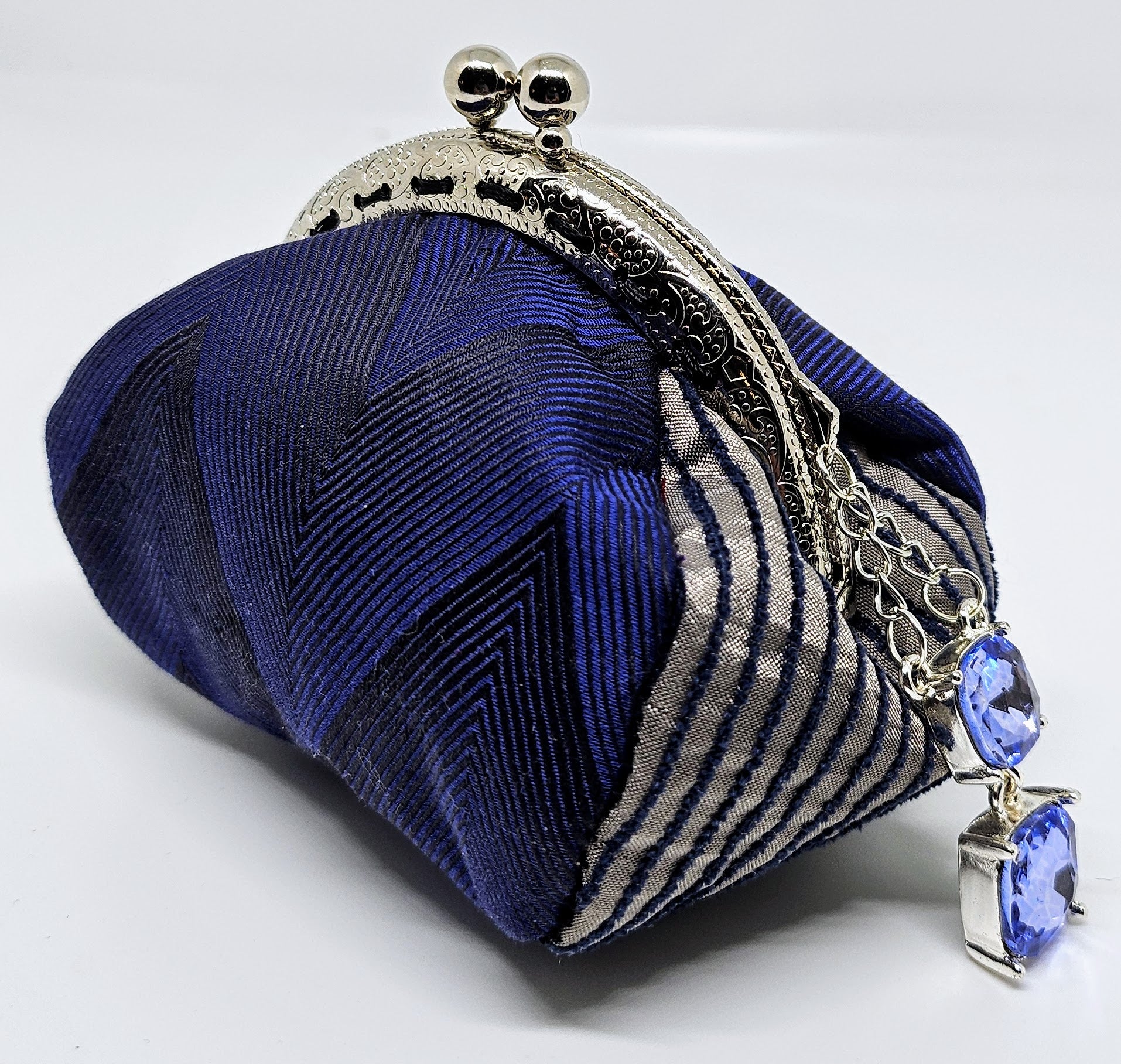Side view of Navy chevron print kiss clasp coin purse with silvery blue jewel charm