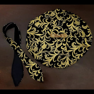 Black and gold damask printed beret with bow detail and matching scarf on brown background
