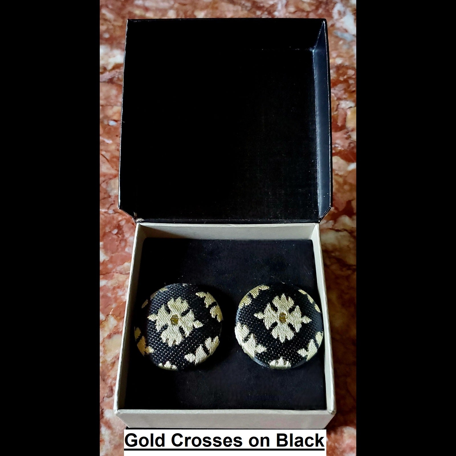 Gold crosses on black print button earrings in jewelry box