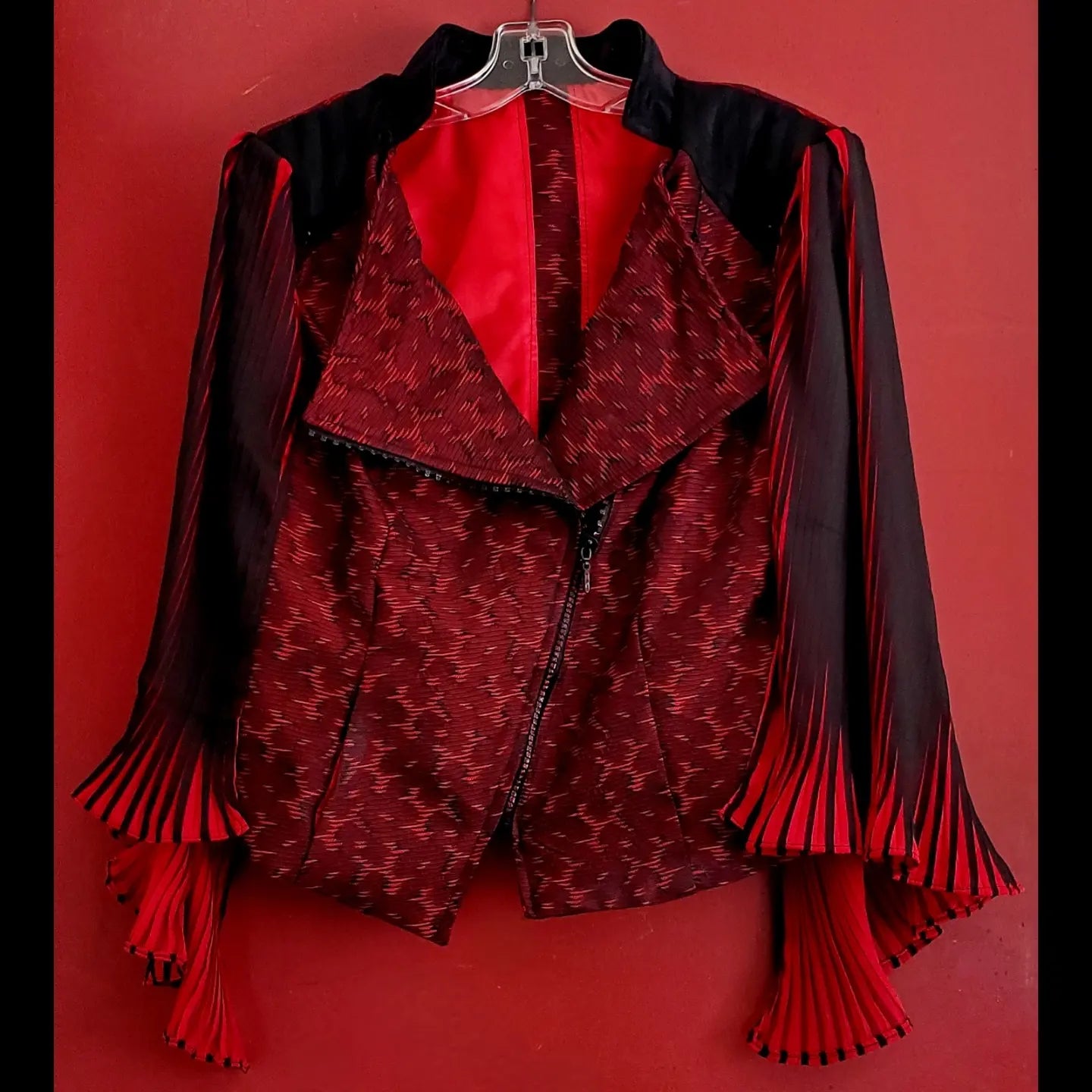 front view of red and black moto jacket with pleated cape sleeves and ruby rhinestone zipper