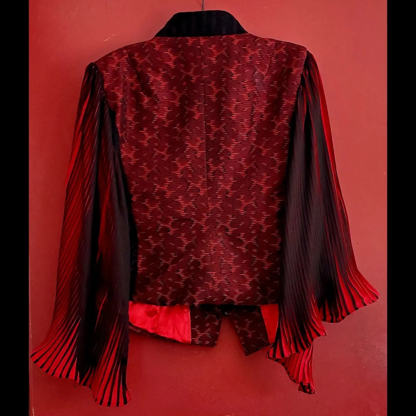 back view of red and black moto jacket with pleated cape sleeves and ruby rhinestone zipper