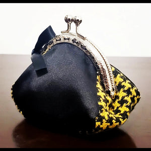 side view of Yellow and black hounds-tooth kiss clasp coin purse with bow