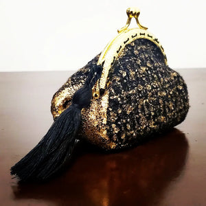 Side view of Gold and black tweed kiss clasp coin purse with tassel