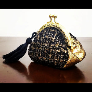side view of Gold and black tweed kiss clasp coin purse with tassel