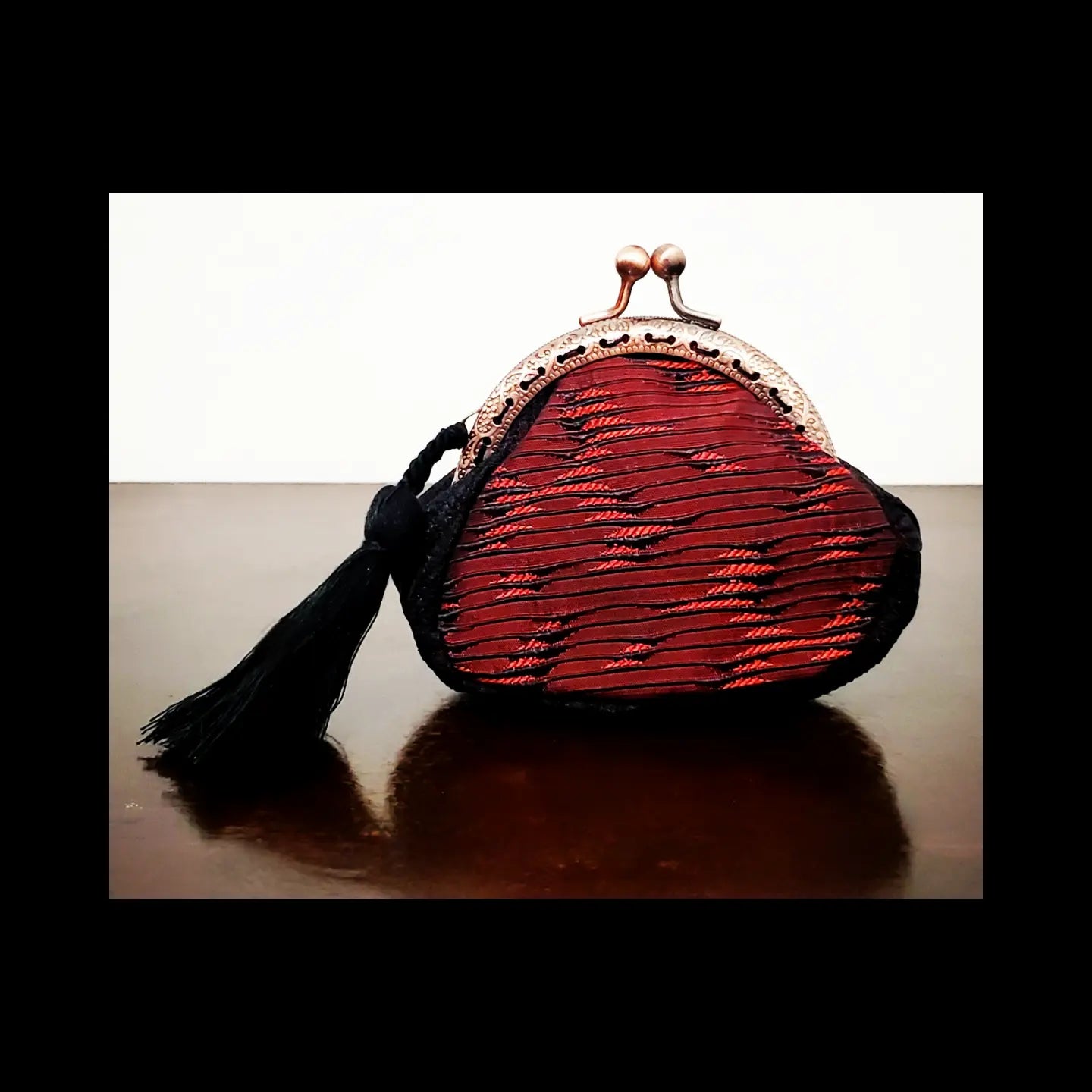 Front view of Red and black brocade coin purse with tassel