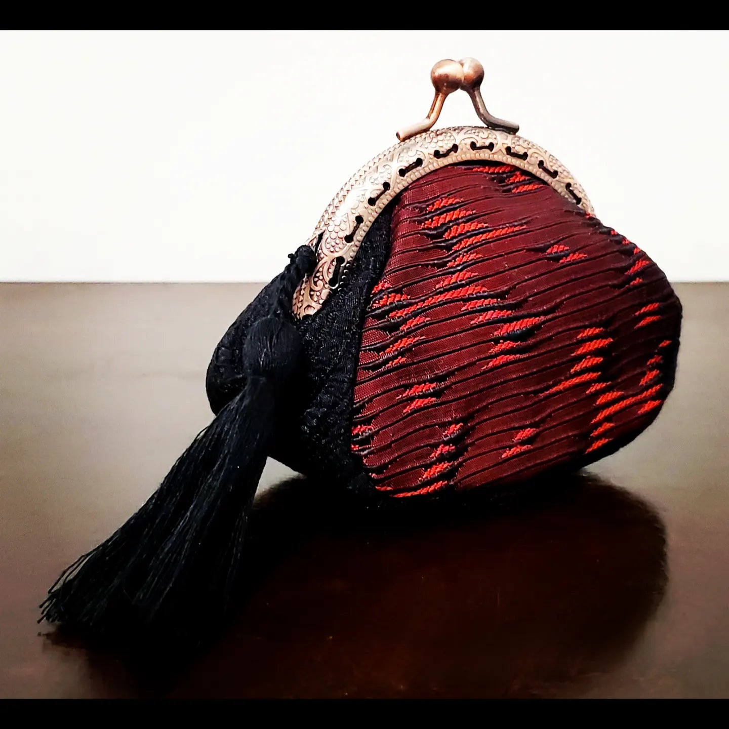 side view of Red and black brocade coin purse with tassel