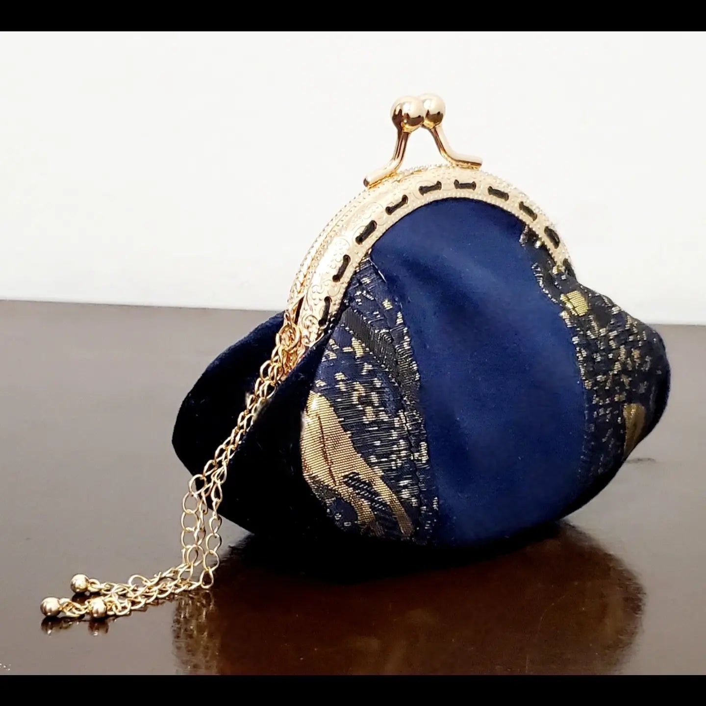 side view of Blue and gold kiss clasp coin purse with gold tassel