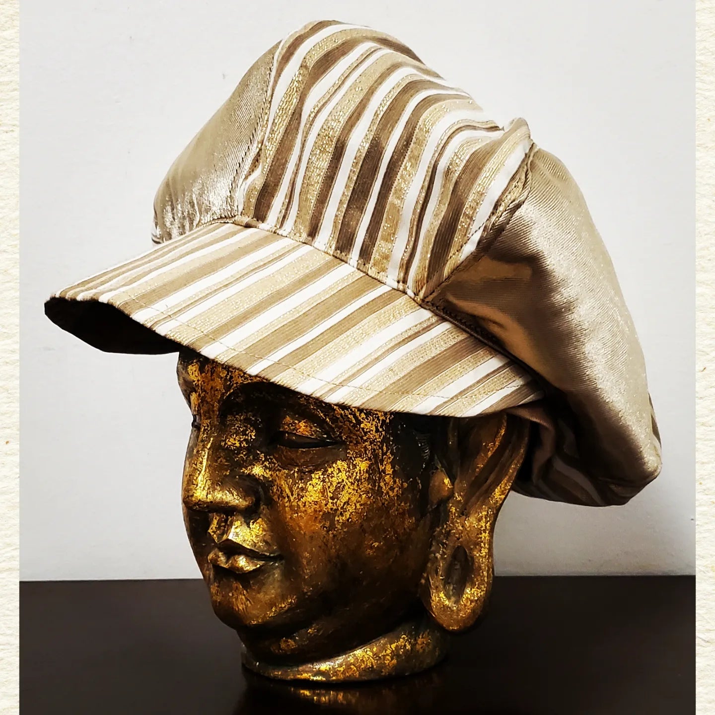 side view of Gold and Ivory striped newsboy hat on mannequin head