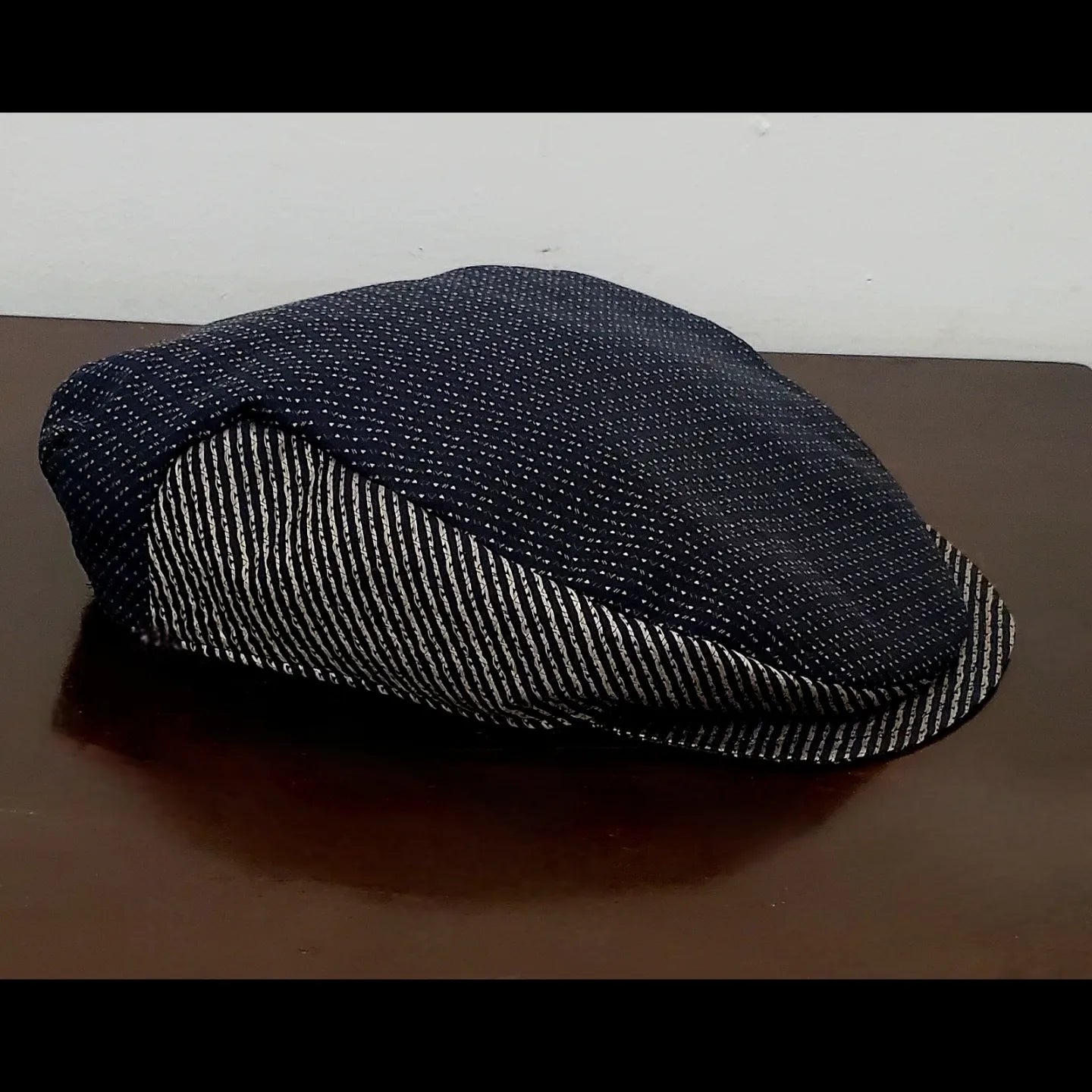 Side view of Brown and black swiss dot and striped flat cap