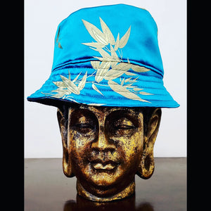 Front view of Teal blue reversible leaf and peacock printed bucket hat