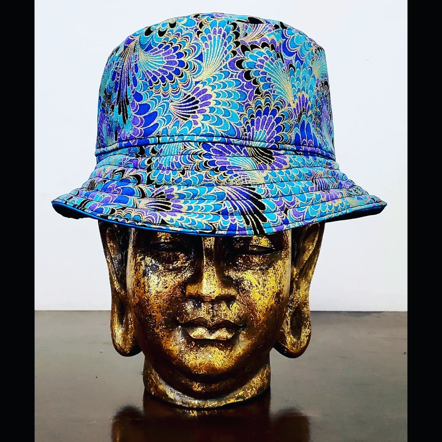 Reversed Front view of Teal blue reversible leaf and peacock printed bucket hat
